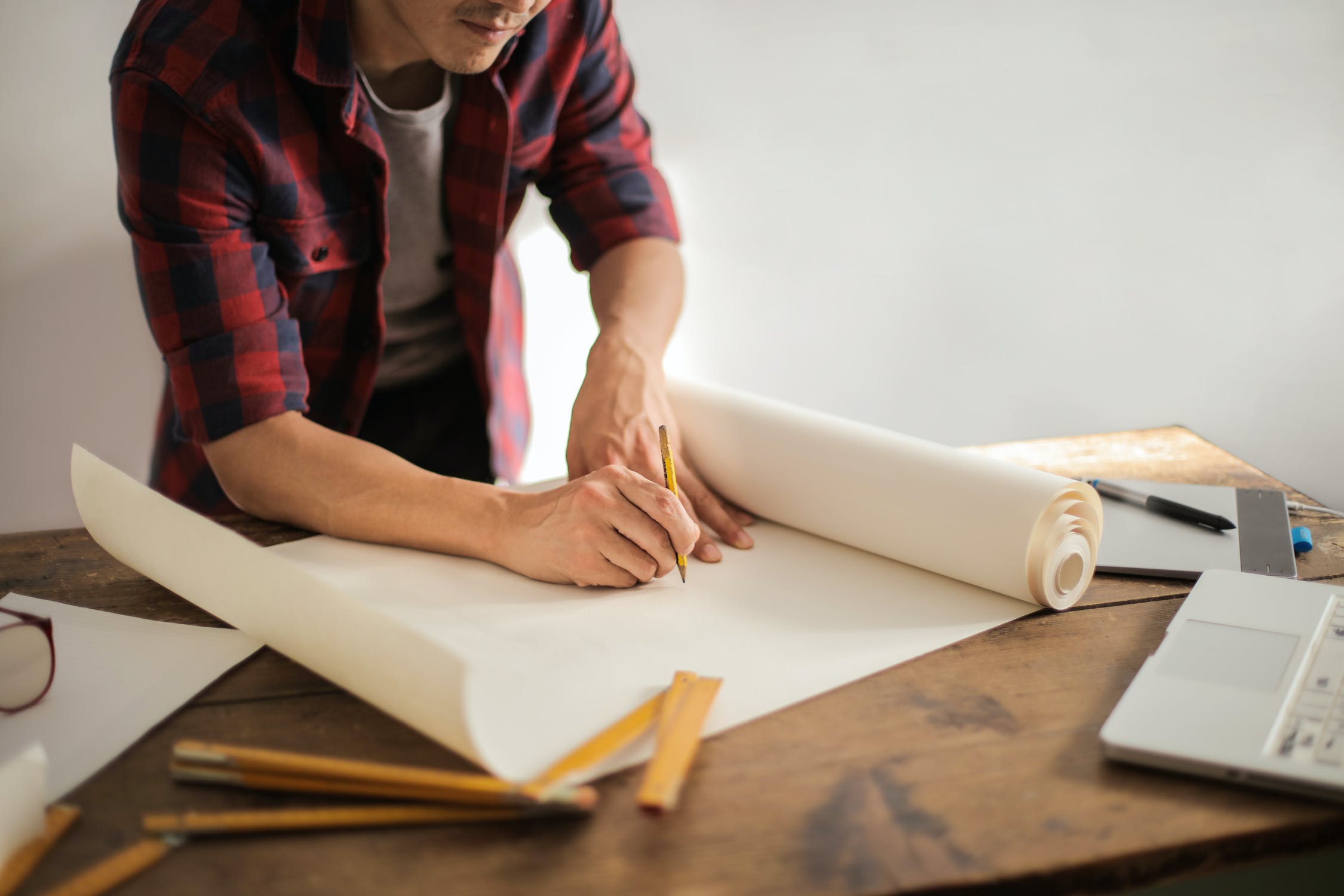 Person holding a pencil about to draw on a large roll of paper 