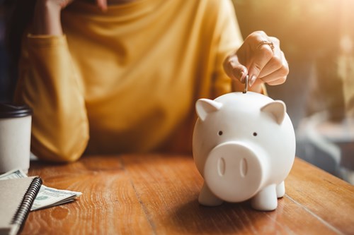 Person putting a coin into a piggy bank