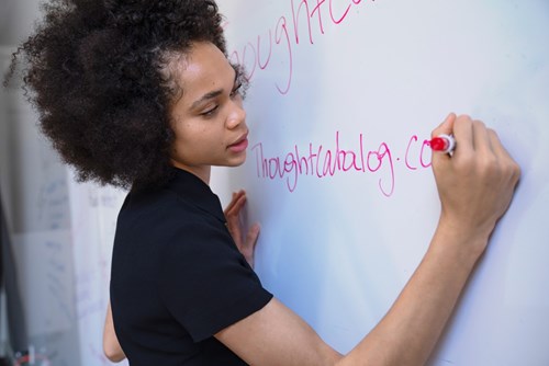 Woman writing on whiteboard with a red pen 
