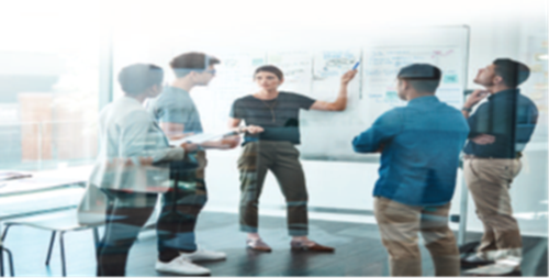 Group of people stood looking at a whiteboard in a glass office 