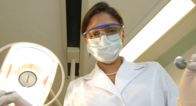 Dentist wearing glasses and facemask about to work on a patient 