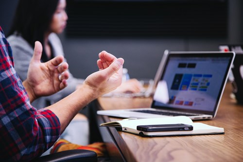 Person talking with hands next to laptop