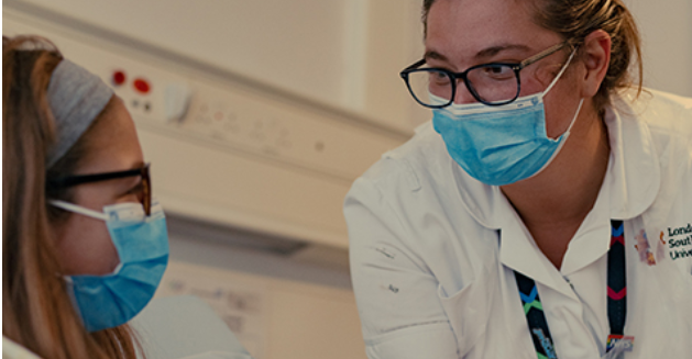 Healthcare support worker with patient both wearing facemasks 