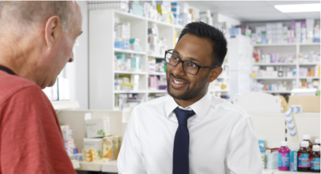 Pharmacist wearing glasses smiling talking to a customer
