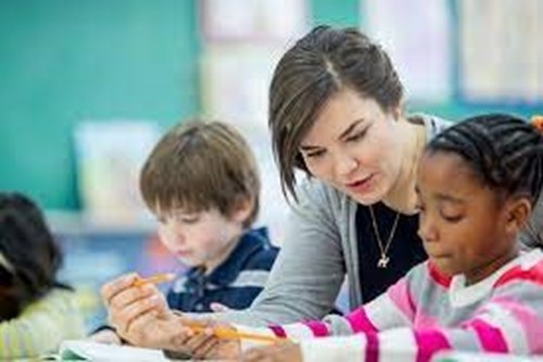 Apprentice teaching assistant helping young students in school 