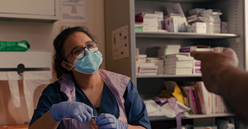 Nurse wearing glasses and a facemask having a conversation 