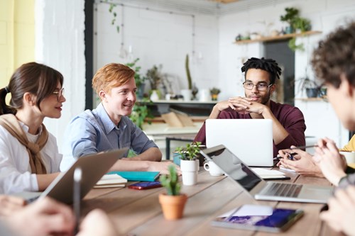 Group In A Meeting Room With Laptops Smiling And Talking