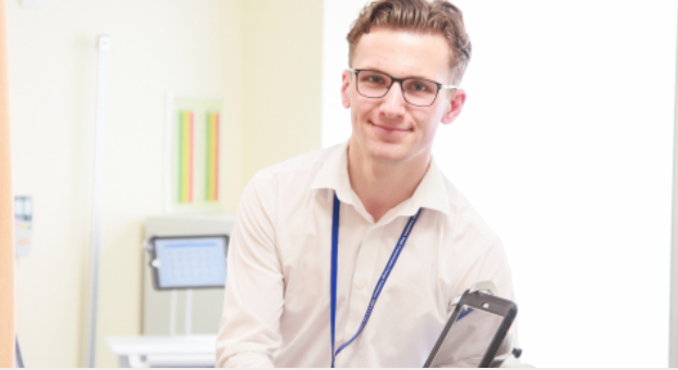 Doctor wearing glasses holding a tablet smiling at the camera 